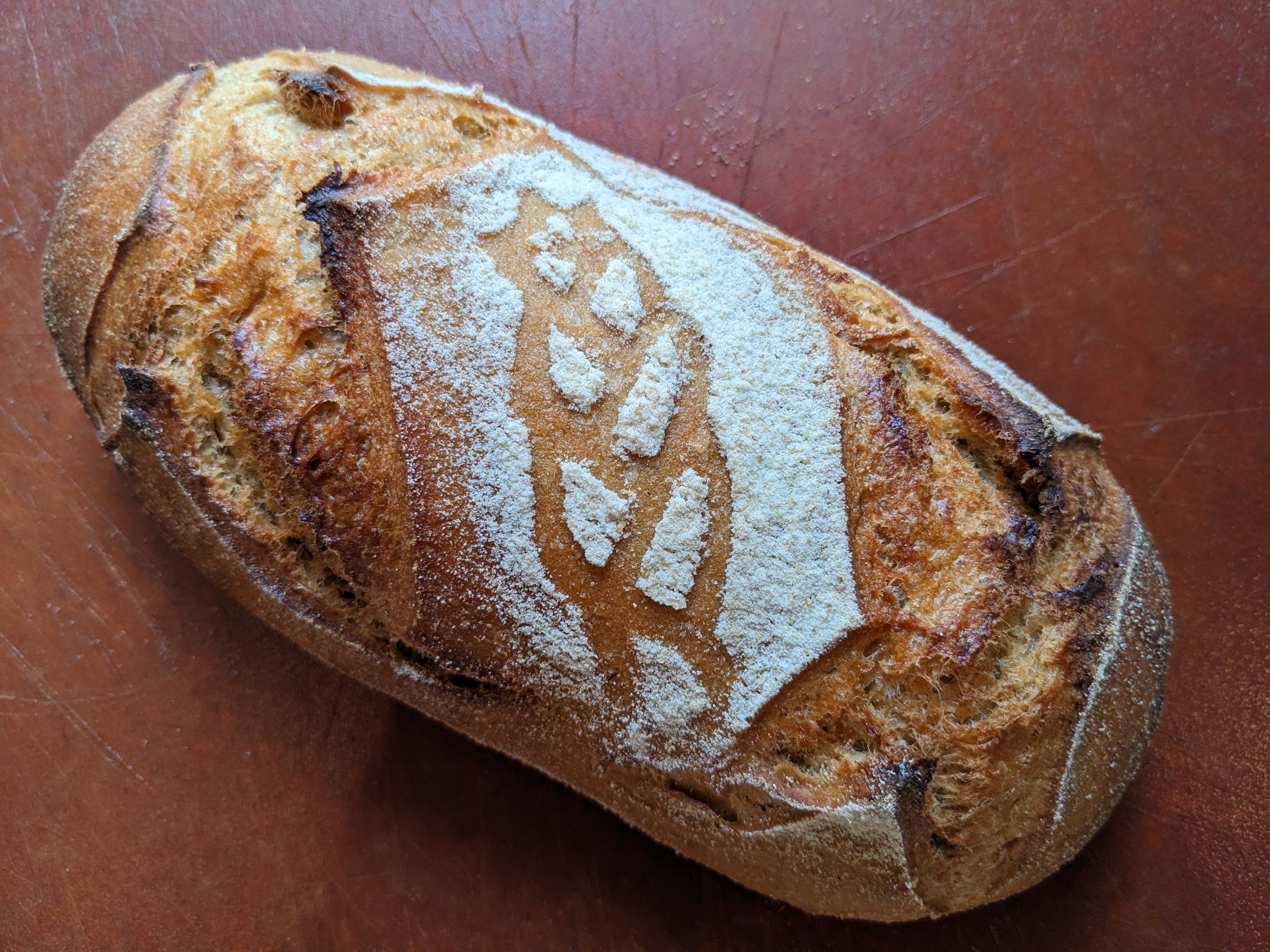 Top view of a loaf of sourdough bread with an image of wheat stenciled on it